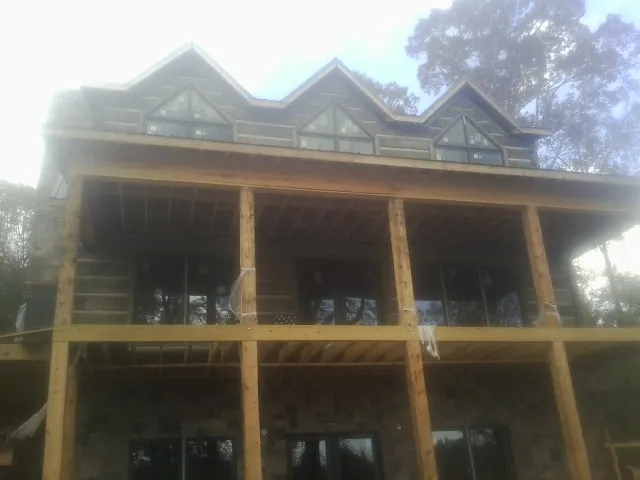 Dormers and porch framing on a large log home under construction — Roof Coating work by our crew in Joanna