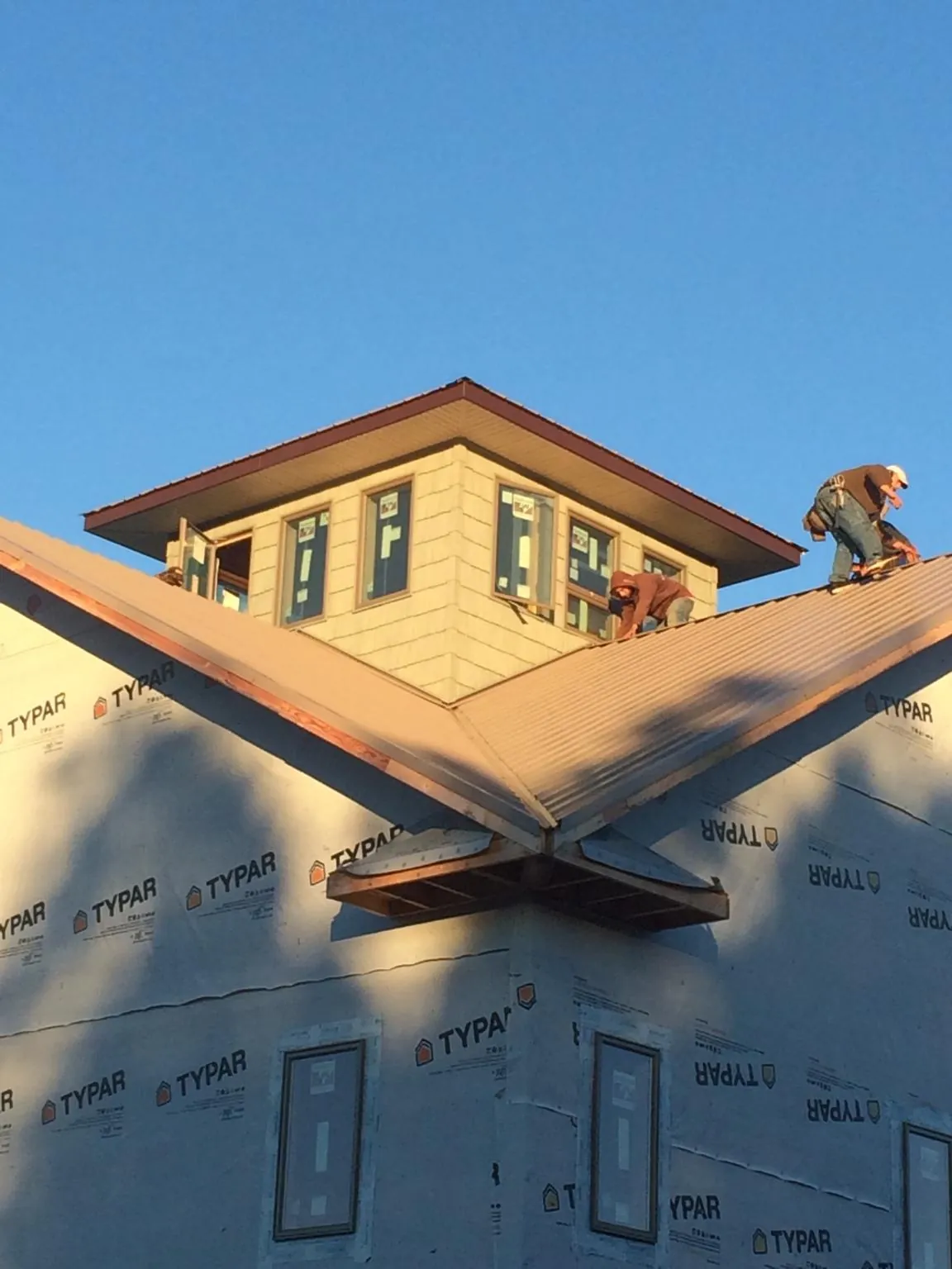 Roofers working around a rooftop cupola on a new metal roof at sunset — Roof Waterproofing in Joanna by Roofing Brothers